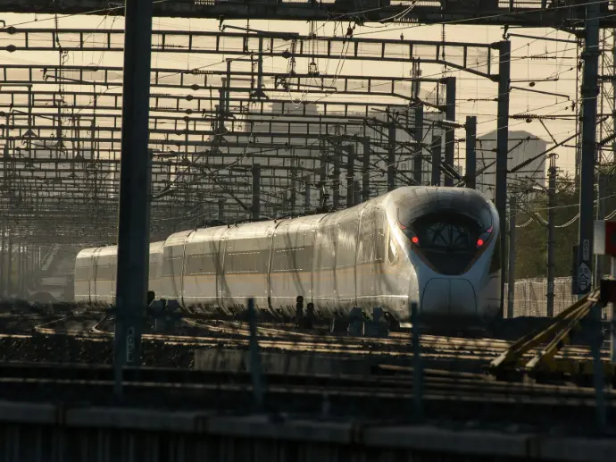 a white train traveling down train tracks next to a forest